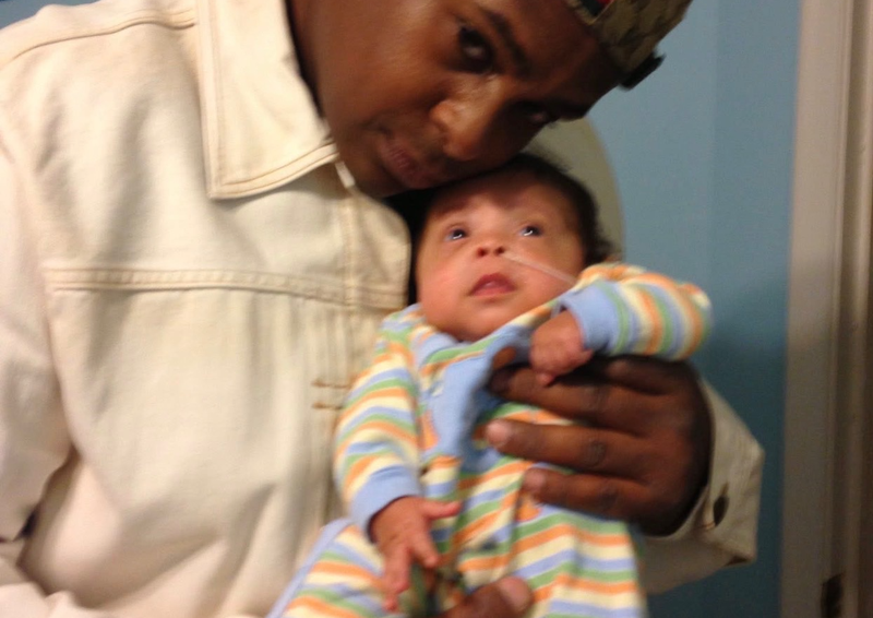 Founder holding his newborn son, DJ, in the NICU.