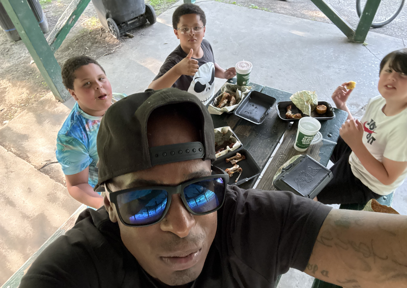Founder with DJ and other children at an outdoor picnic table.